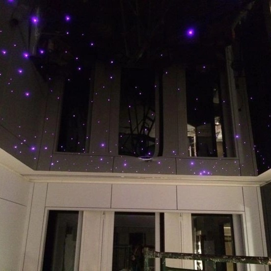 Nowoczesne wnętrze z podwieszanym sufitem w kolorze ciemnego grafitu, oświetlonym małymi, fioletowymi diodami LED imitującymi gwiazdy, widok z dołu.