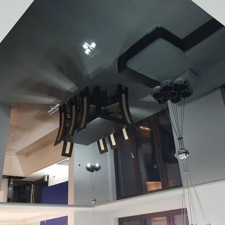 Czarny, błyszczący sufit z oświetleniem punktowym i dekoracyjną lampą, odbijający elementy wnętrza. Nowoczesny design wnętrza.
