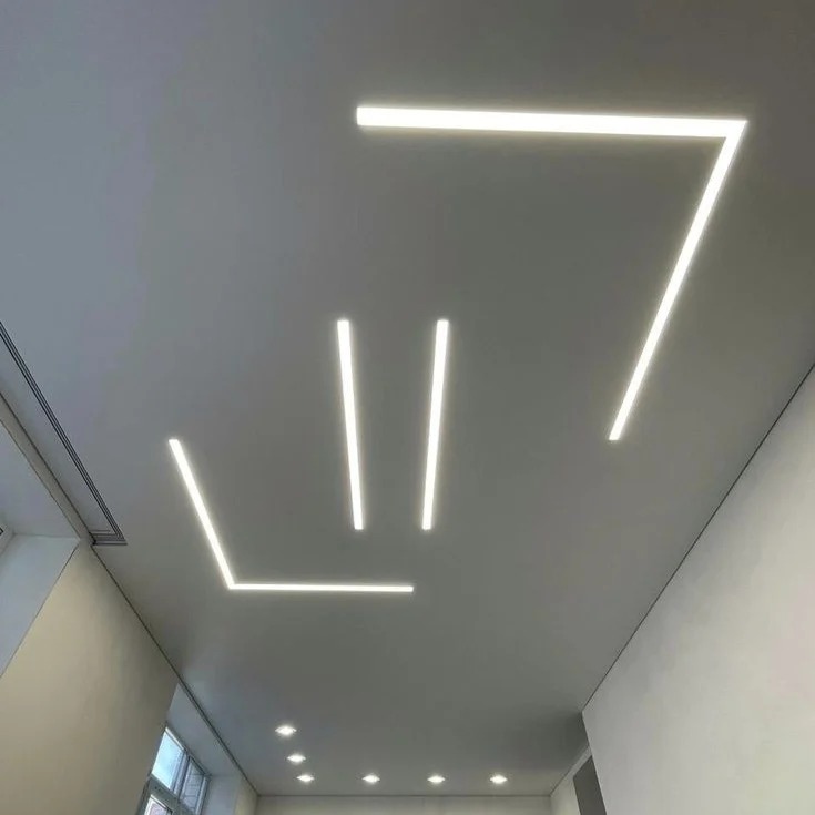 Nowoczesny sufit z liniowym oświetleniem LED tworzącym geometryczne wzory. Minimalistyczny design, jasne światło, gładka powierzchnia sufitu.