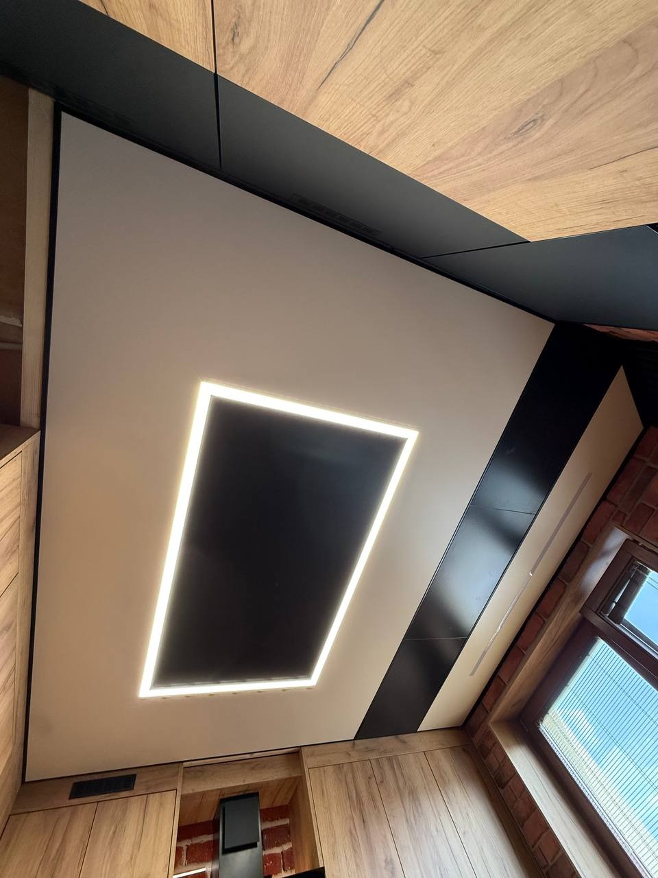 Nowoczesny sufit z podświetleniem LED w kształcie prostokąta, czarny pas dekoracyjny, drewniane wykończenie ścian i sufitu, widok z dołu, wnętrze po remoncie.