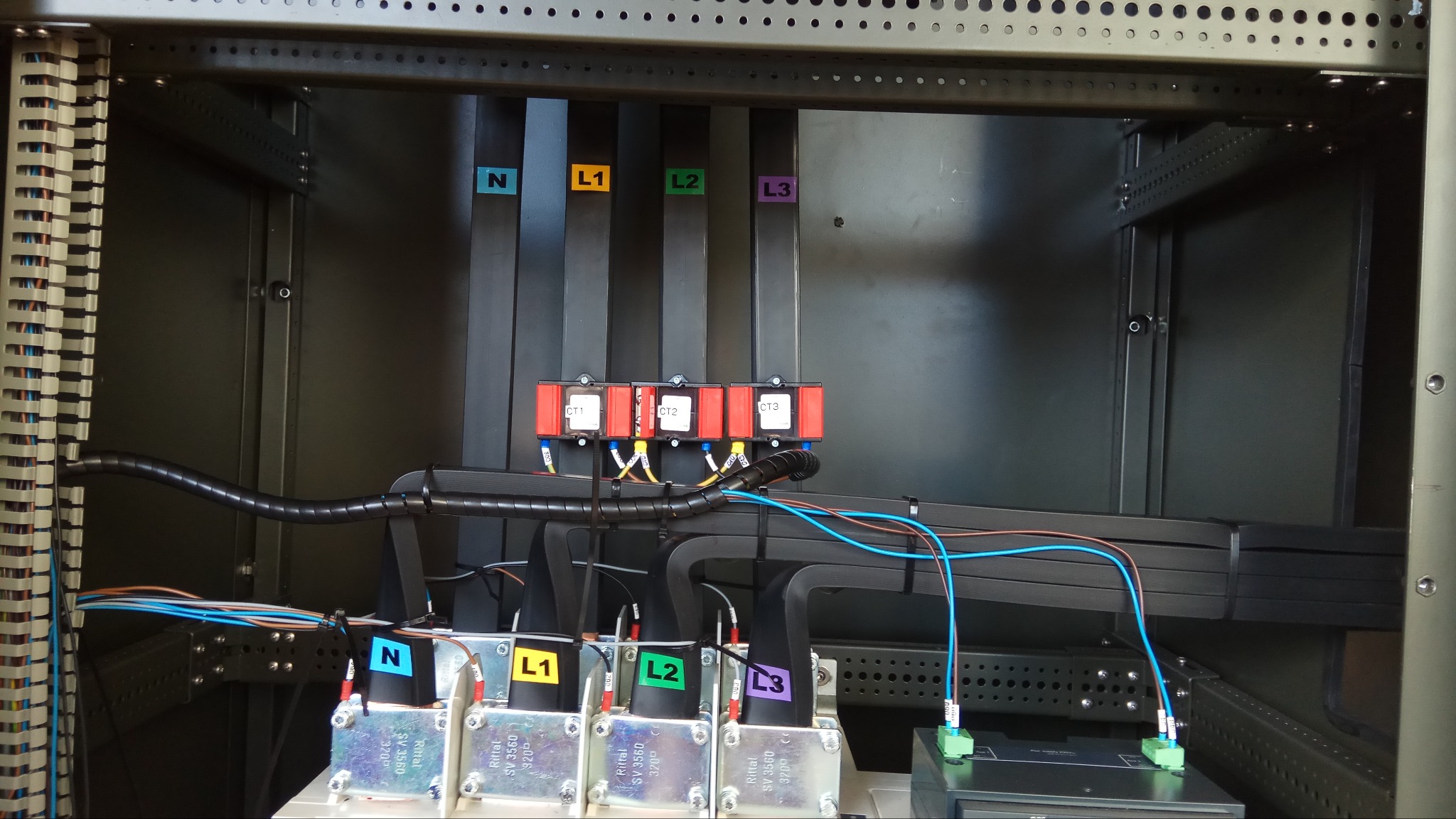 Wnętrze szafy elektrycznej z okablowaniem oznaczonym kolorowymi etykietami L1, L2, L3 i N. Widoczne elementy instalacji, zabezpieczenia i przewody.