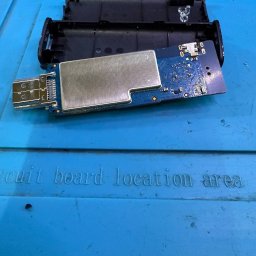 KARACA LIMITED - Otwarty moduł elektroniczny z USB i elementami na płytce, leżący na niebieskiej macie z napisem 'circuit board location area'.