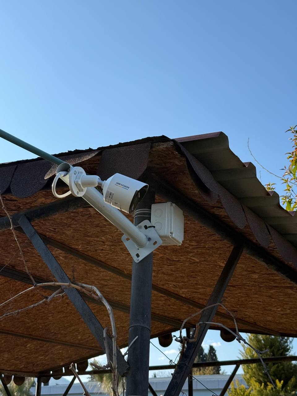 Kamera monitoringu Hikvision zamontowana na zadaszeniu w Warszawie. Widok z dołu, niebieskie niebo w tle. Zabezpieczenia i ochrona w zasięgu wzroku.