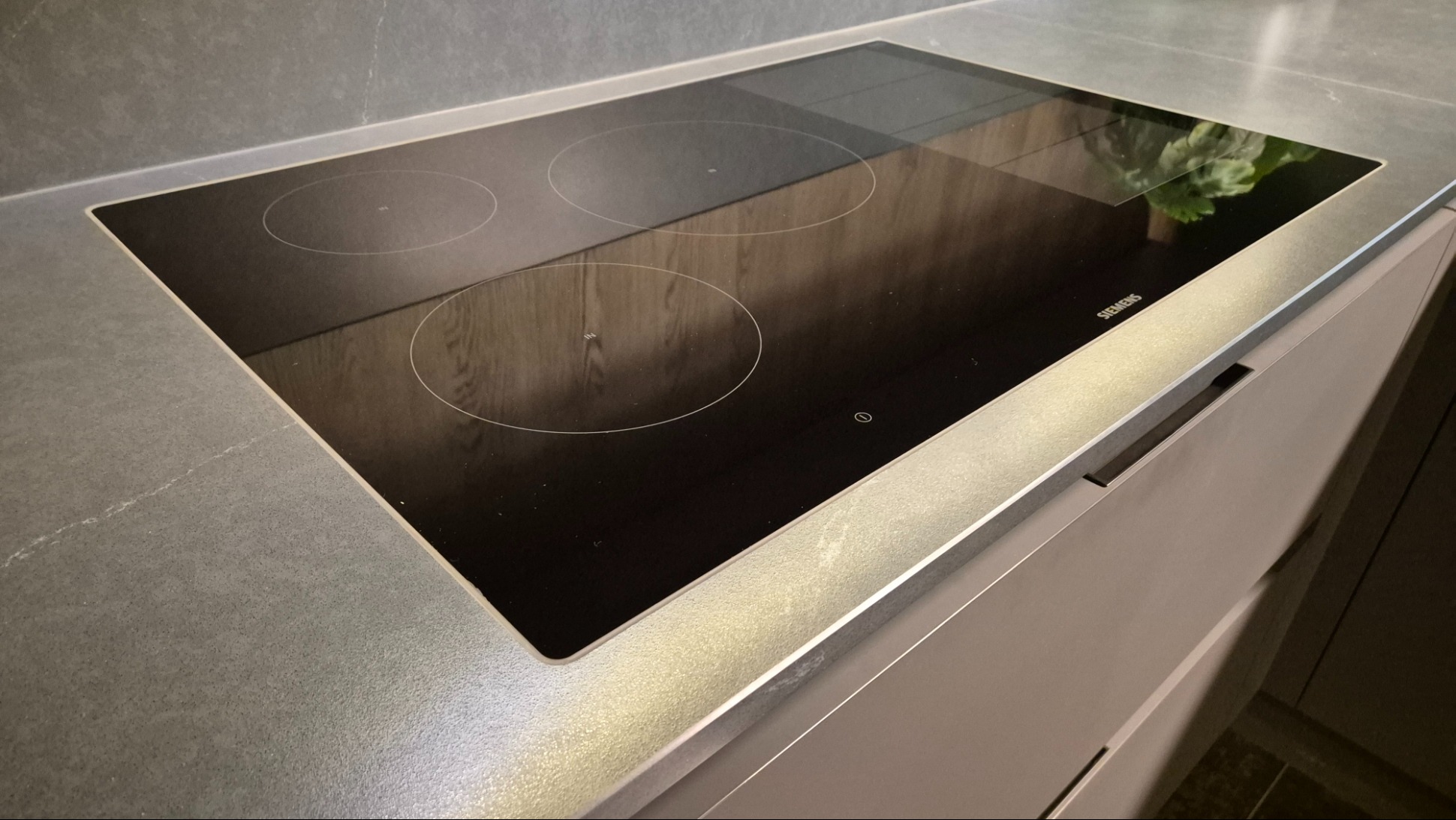 Ciemnoszary blat z konglomeratu kwarcowego Silestone z wbudowaną płytą indukcyjną Siemens. Matowa powierzchnia z subtelnymi żyłkami i nowoczesny sprzęt.
