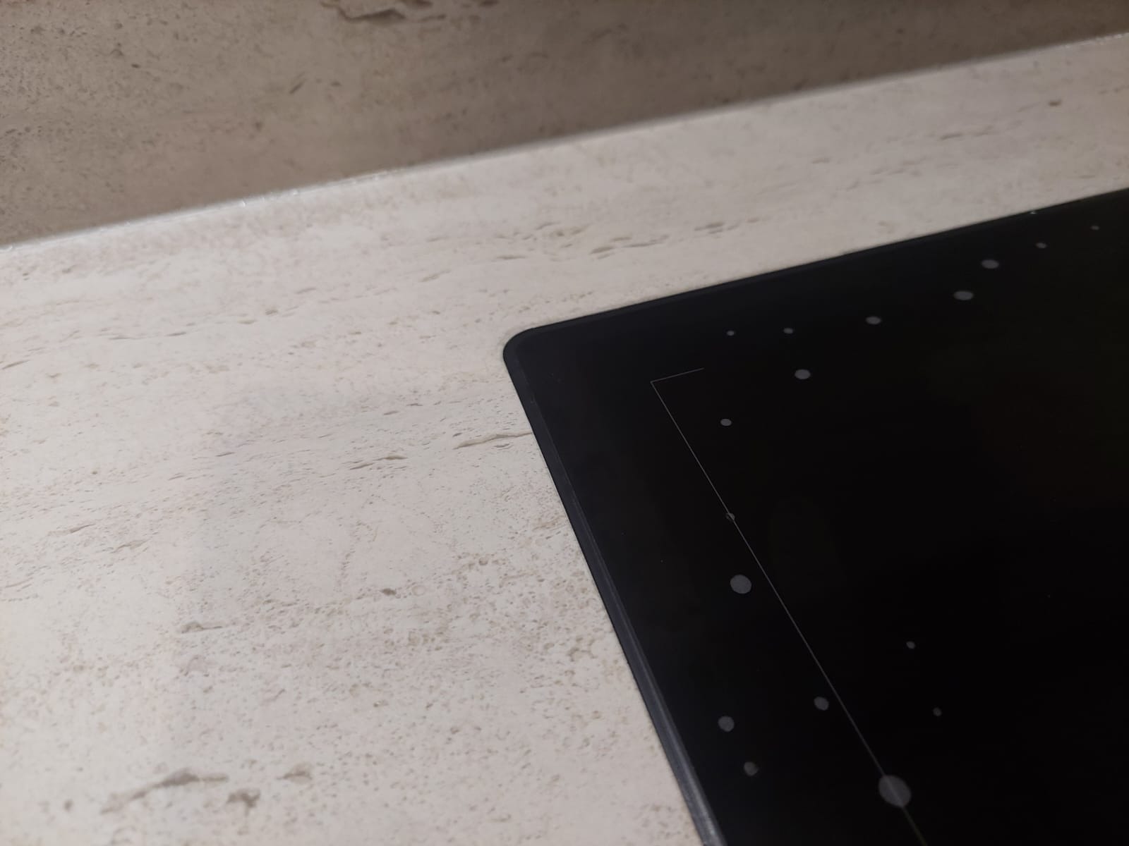 Detale zlicowanego blatu kamiennego Dekton Marmorio Pietra z subtelnym użyleniem i matowym wykończeniem, przylegającego do czarnej płyty indukcyjnej.