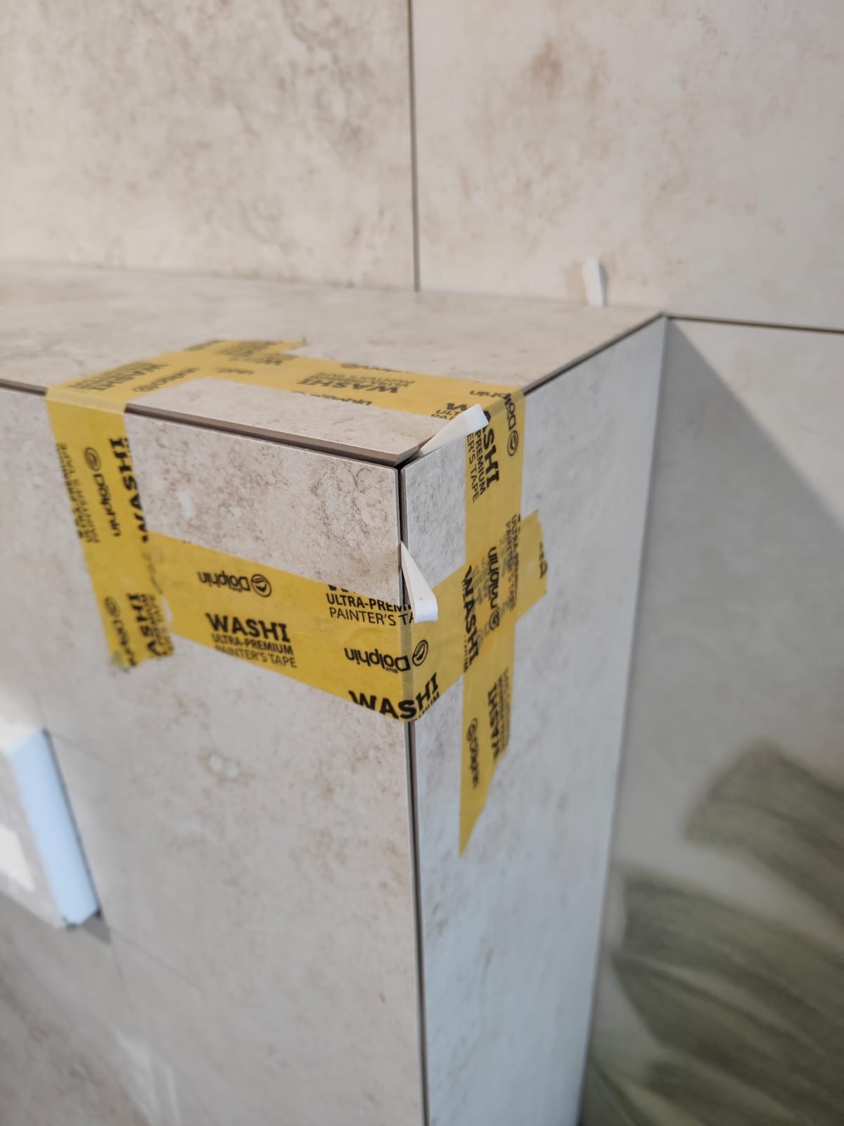 Detal płytek narożnych zabezpieczonych taśmą malarską Washi, zbliżenie na fragment wykończenia ściany w neutralnej kolorystyce.