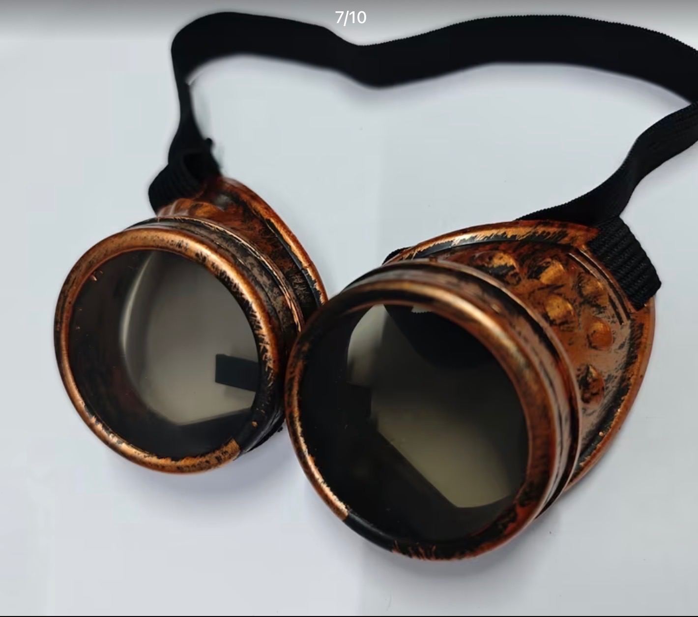 Miedziane gogle steampunk z czarnym paskiem na białym tle, detale zdobień i metaliczne wykończenie, rekwizyt na imprezę tematyczną.