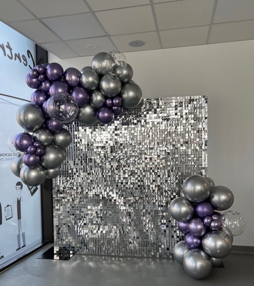 Srebrno-fioletowa ścianka z cekinów i balonów, idealna na imprezę w Warszawie. Dekoracja z balonów w odcieniach szarości i fioletu, błyszcząca ścianka.