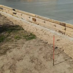 M-Bud Przemysłówka - Wylewka betonowa na placu budowy, widoczne drewniane szalunki i sprzęt ciężki w tle. Świeżo wylany beton tworzy gładką powierzchnię.