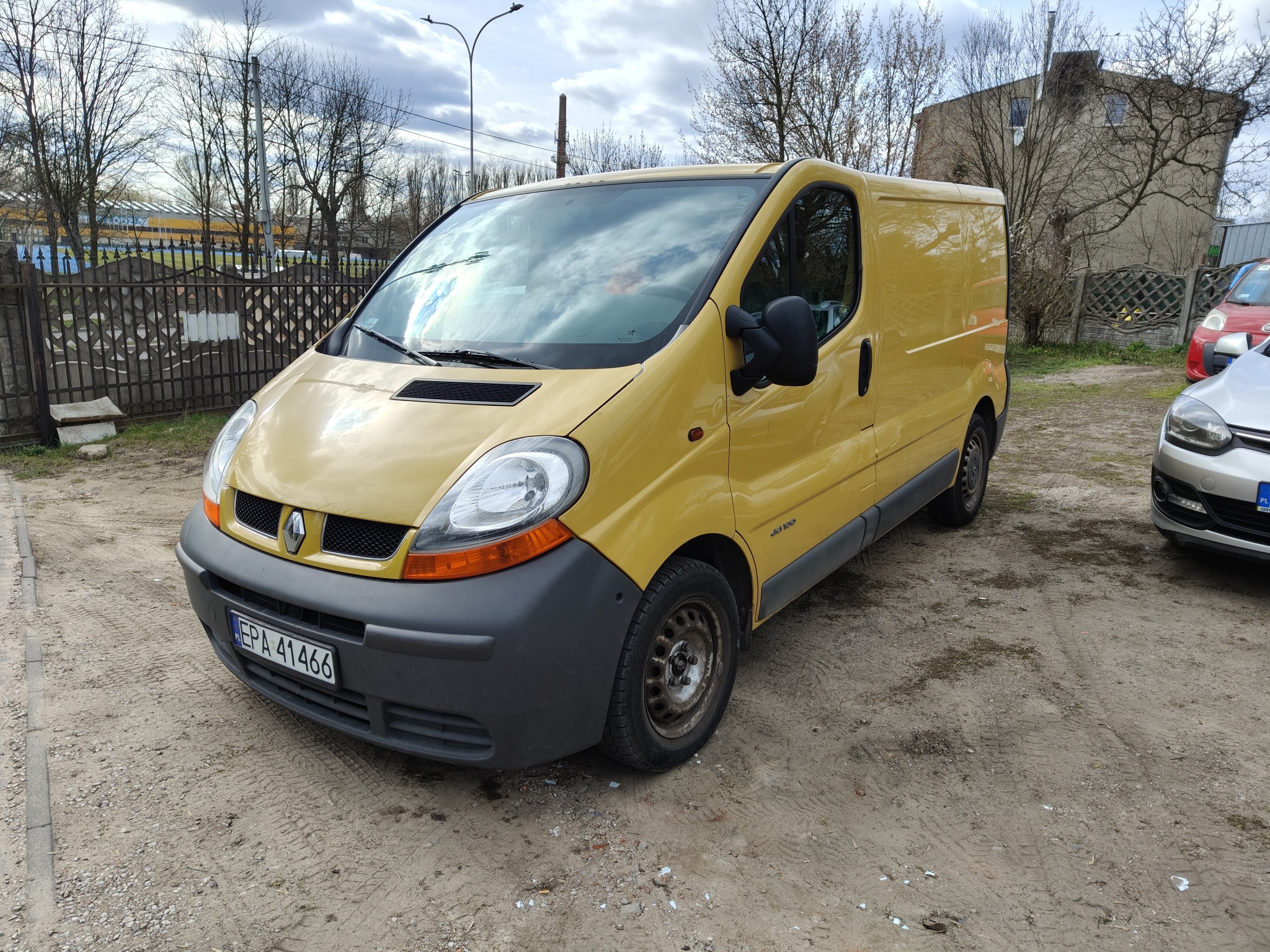 Żółty Renault Trafic, widok z przodu na placu z ubitym piaskiem. Na tablicy rejestracyjnej widnieje numer EPA 41466.