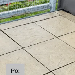 Wyłożona jasna kostka brukowa na balkonie z metalową barierką w tle, widok z góry, etap po zakończeniu prac, czysta powierzchnia.