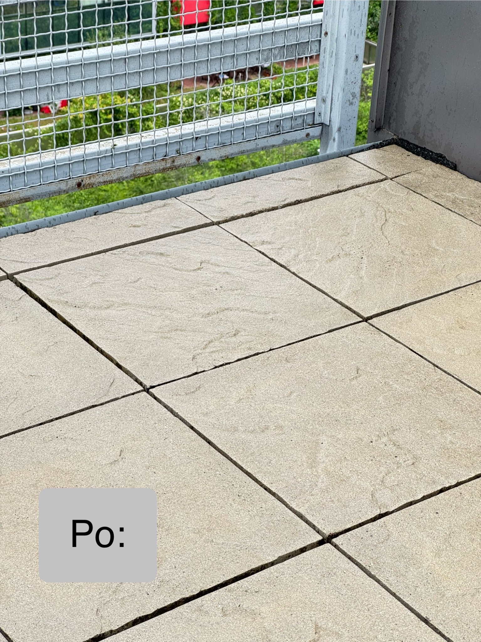 Wyłożona jasna kostka brukowa na balkonie z metalową barierką w tle, widok z góry, etap po zakończeniu prac, czysta powierzchnia.