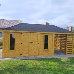 Mateusz Stronczek - Drewniany domek narzędziowy z dwuspadowym dachem krytym gontem bitumicznym, z oknami i podwójnymi drzwiami, zadaszony taras boczny, na kostce brukowej, otoczony zielonym trawnikiem.