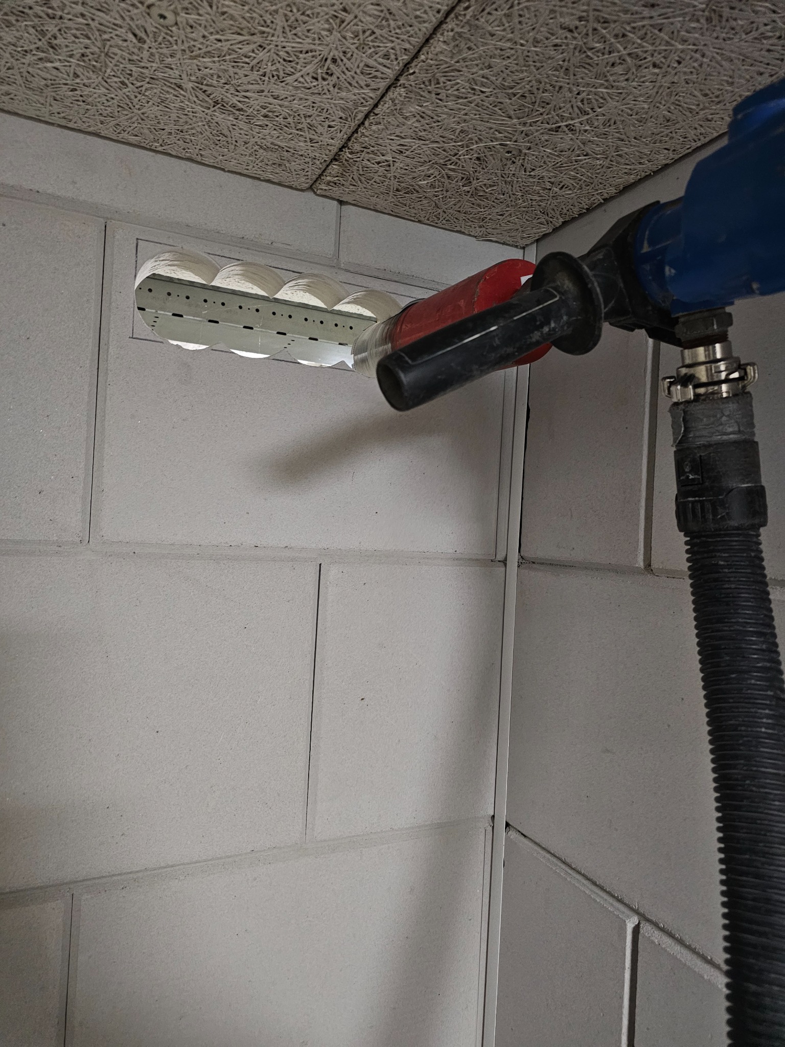 Wiercenie otworów w ścianie z betonu komórkowego za pomocą wiertnicy diamentowej z odsysaniem pyłu. Widoczne równe, okrągłe otwory w ścianie.