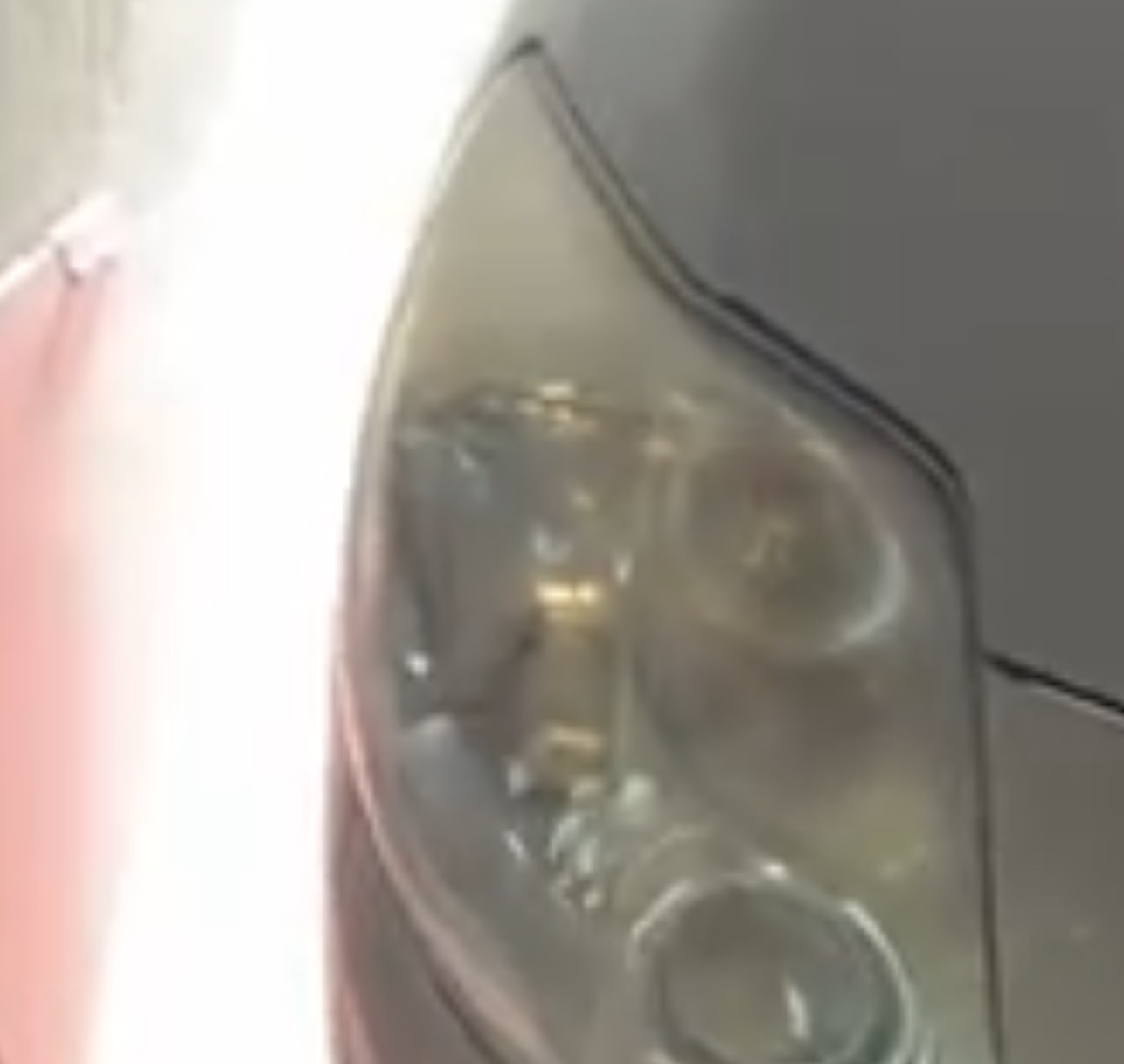 Reflektor samochodowy z widocznymi śladami zużycia i zmatowienia, wymagający renowacji. Widoczne detale konstrukcyjne lampy.