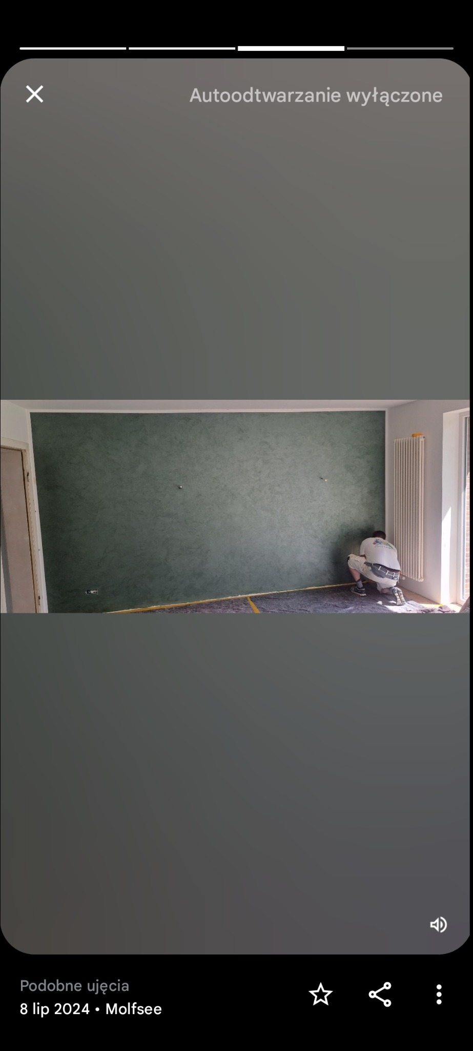 Pokój po malowaniu dekoracyjnym ścian na zielono, zabezpieczona podłoga, grzejnik, pracownik w trakcie prac wykończeniowych, widok na ścianę z efektem dekoracyjnym.