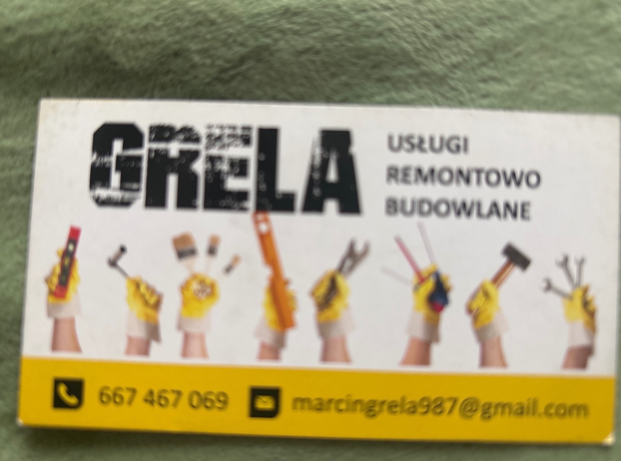 Wizytówka firmy budowlanej z nazwą 'Grela' i numerem telefonu. Grafika z dłońmi w rękawicach trzymających narzędzia.