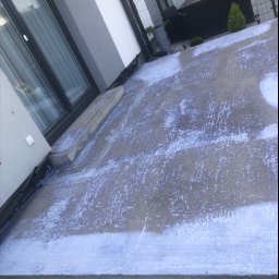 Vasyl Boiko - Świeża, wilgotna wylewka betonowa na tarasie przylegającym do domu jednorodzinnego, z widocznymi śladami po zacieraniu. Na drugim planie meble ogrodowe.