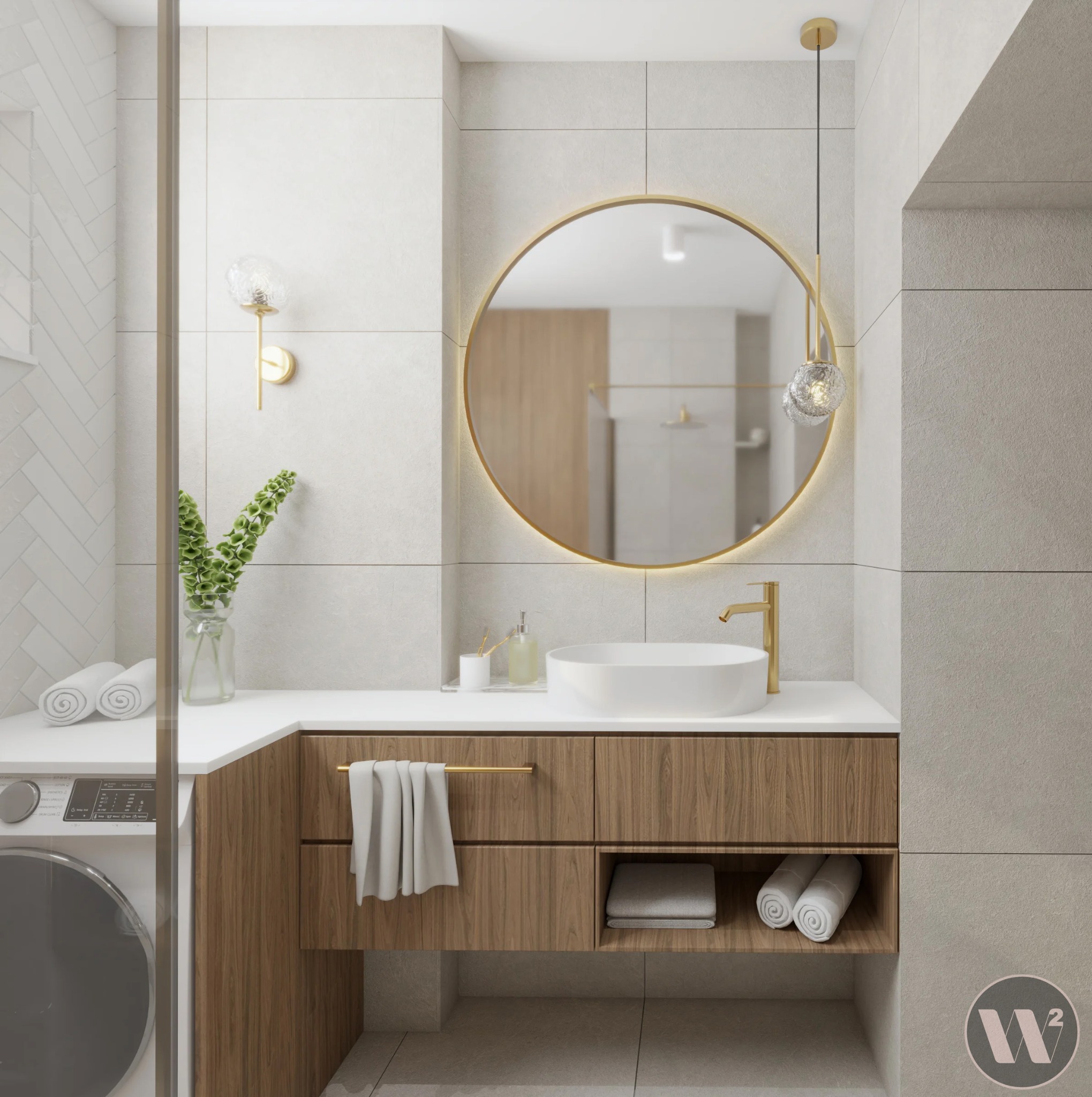 Nowoczesna łazienka z okrągłym lustrem w złotej ramie, drewnianą szafką pod umywalką i pralką schowaną za szklaną ścianką. Minimalistyczny design i stonowana kolorystyka.
