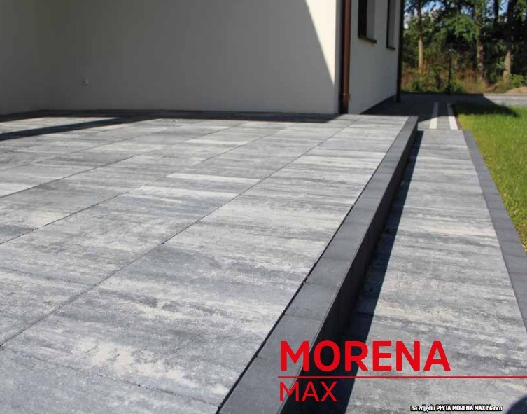 Szara, płaska kostka brukowa 'Morena Max' ułożona na podjeździe przed budynkiem. Widoczne obrzeża i trawnik. Minimalistyczny design, nowoczesne wykończenie.