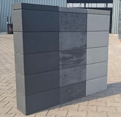 Prezentacja różnorodności faktur i kolorów na prefabrykowanych elementach betonowych ułożonych w kolumnę. Widoczne detale powierzchni i subtelne różnice w odcieniach szarości.