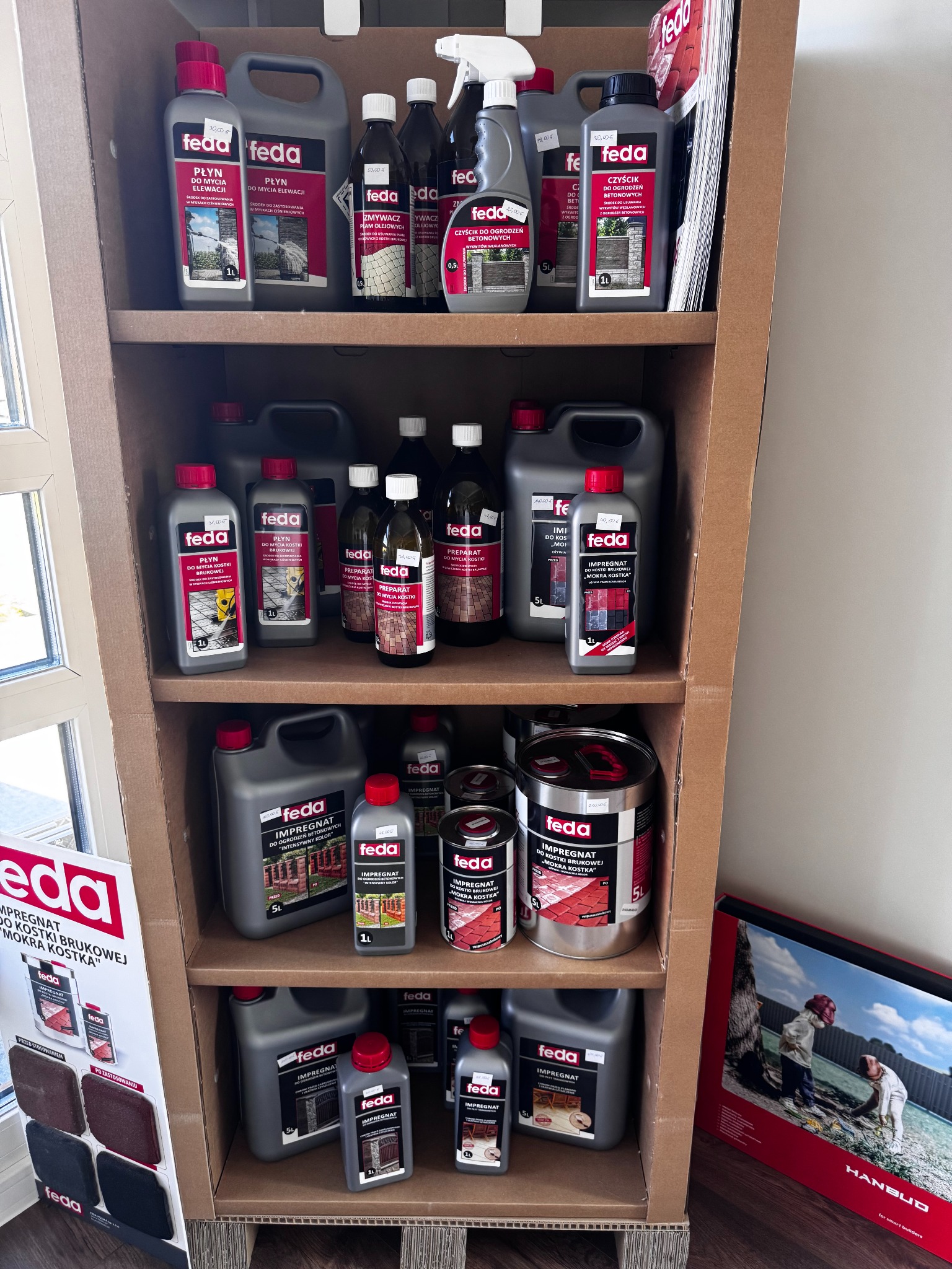 Ekspozycja produktów Feda: płyny do mycia elewacji i kostki brukowej, impregnaty do ogrodzeń betonowych i kostki brukowej,  w regale kartonowym.