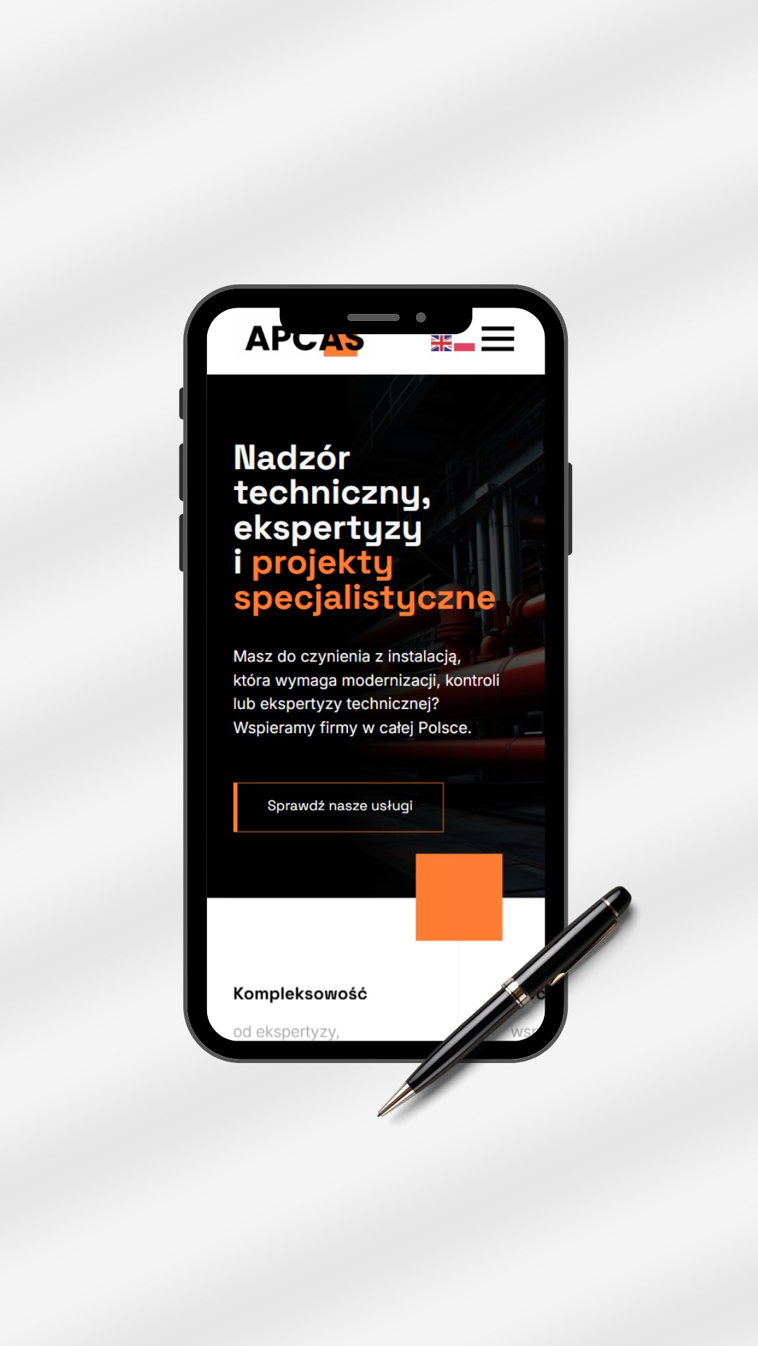 Ekran smartfona prezentuje stronę internetową firmy APCAS z hasłem 'Nadzór techniczny, ekspertyzy i projekty specjalistyczne'. Obok leży czarny długopis.