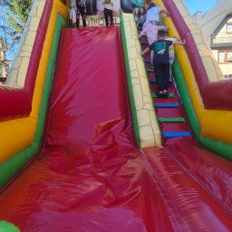 Dinofun Zakopane - Kolorowa dmuchana zjeżdżalnia z motywem goryla i wspinaczką, na której bawi się grupa dzieci w słoneczny dzień. Atrakcja plenerowa.