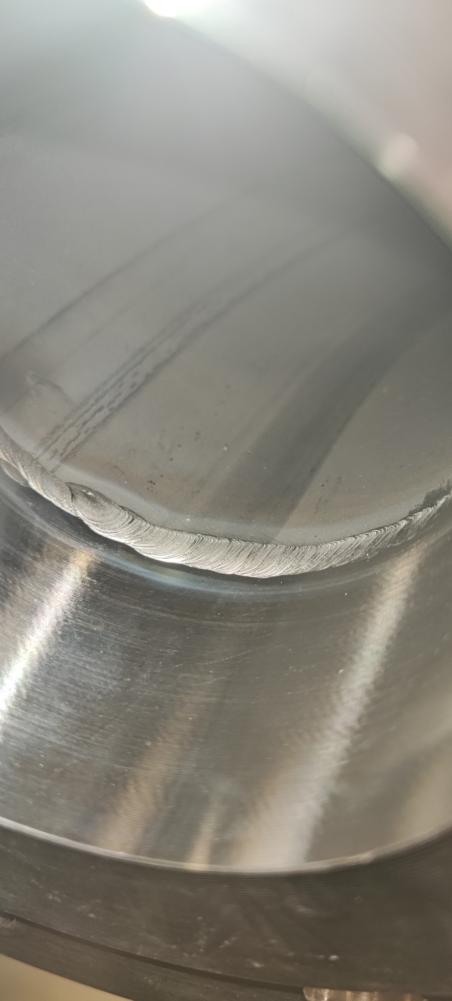 Wnętrze metalowej rury z widocznym, precyzyjnym spawem okrężnym. Charakterystyczne ślady obróbki i spawania na powierzchni metalu.