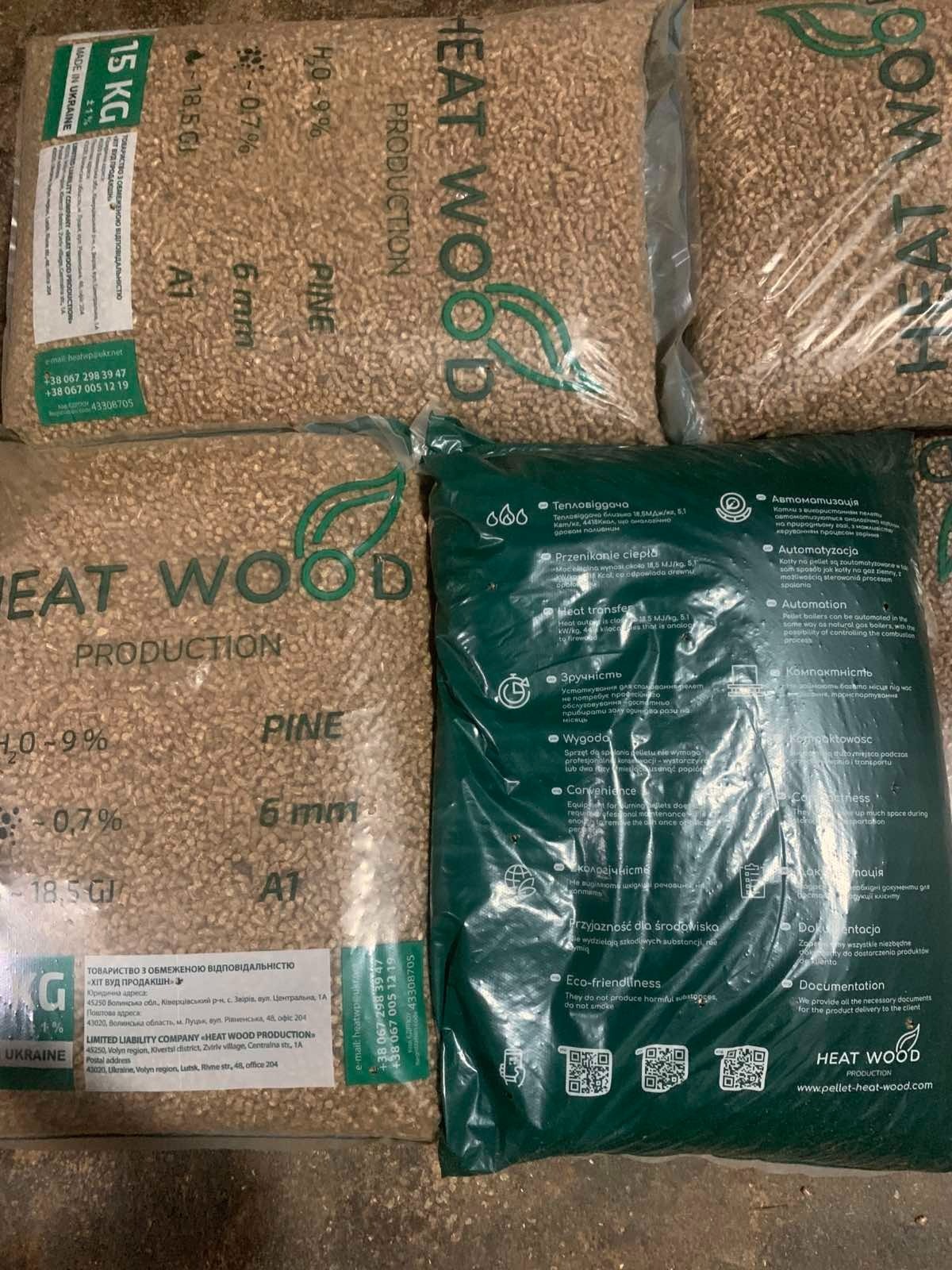 Worki z pelletem drzewnym Heat Wood Production, w tym jeden zielony z napisem 'Eco-friendliness' i kodami QR. Widoczne parametry: H2O-9%, 6mm, 18,5 GJ.