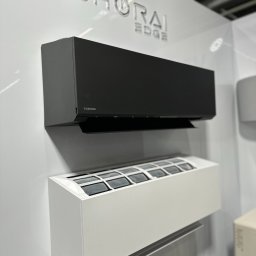 PSD SPÓŁKA Z OGRANICZONĄ ODPOWIEDZIALNOŚCIĄ - Dwa klimatyzatory Toshiba Shoriai Edge: czarny i biały, zamontowane na ścianie. Widoczny filtr w białym urządzeniu. Minimalistyczny design i nowoczesny wygląd.