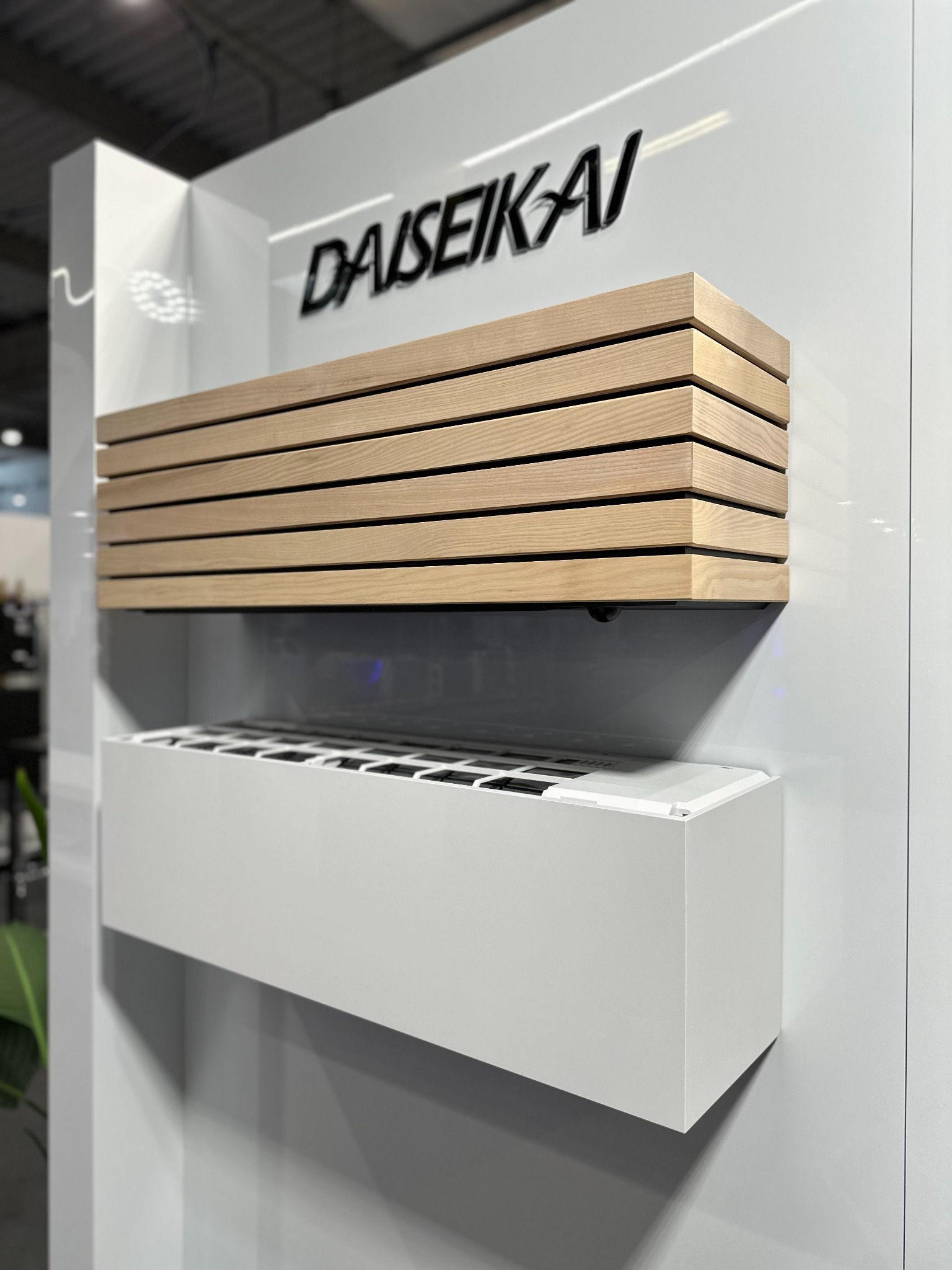 Nowoczesna klimatyzacja DAISEIKAI z drewnianą obudową, zamontowana na białej ścianie. Minimalistyczny design, widoczne detale wykończenia.