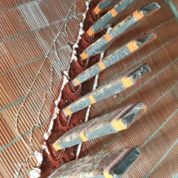 Montaż ocieplenia od wewnątrz: styropianowe płyty zabezpieczone folią, mocowane do ściany z cegły za pomocą pianki montażowej i stalowych kotew. Widoczne przewody elektryczne.