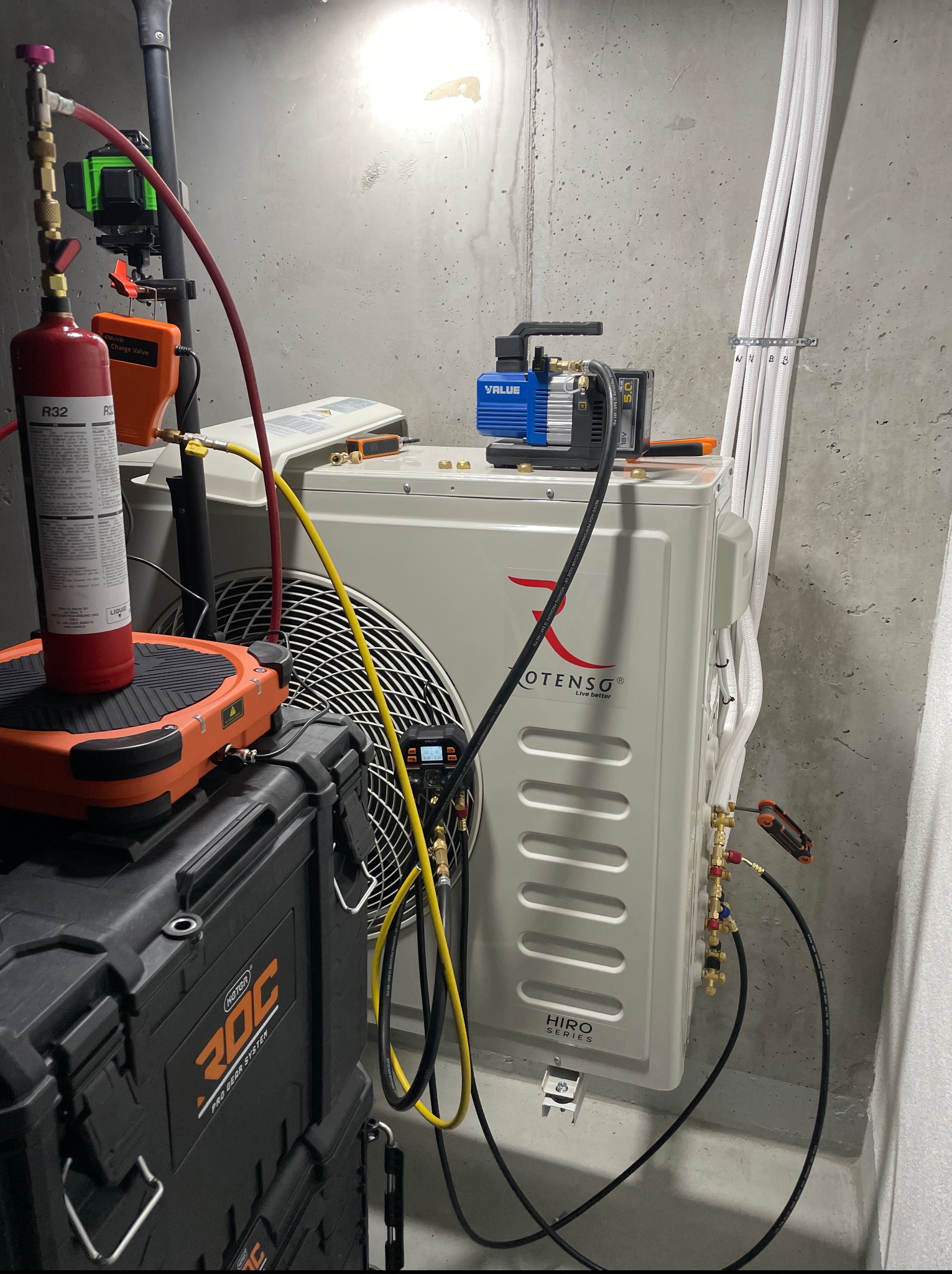 Montaż klimatyzacji: jednostka zewnętrzna Rotenso HIRO Series, butla R32, pompa próżniowa VALUE i zestaw narzędzi RDC. Instalacja w surowym pomieszczeniu.