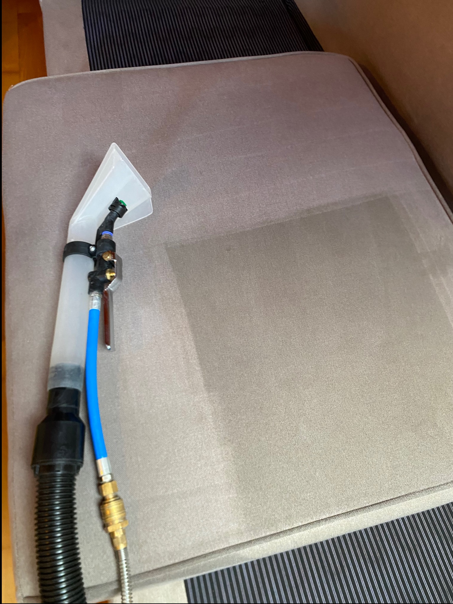 Fragment sofy z widocznym efektem czyszczenia tapicerki przy użyciu specjalistycznego sprzętu. Widoczna różnica w kolorze po praniu.