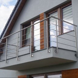 NAJDEK PRO SPÓŁKA Z OGRANICZONĄ ODPOWIEDZIALNOŚCIĄ - Nowoczesny balkon z szarą elewacją i balustradą ze stali nierdzewnej, widok na okna z drewnianymi ramami i częściowo widoczną anteną satelitarną.