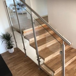 NAJDEK PRO SPÓŁKA Z OGRANICZONĄ ODPOWIEDZIALNOŚCIĄ - Nowoczesne schody z drewnianymi stopniami i szklaną balustradą z elementami ze stali nierdzewnej. Widok z góry, naturalne oświetlenie.