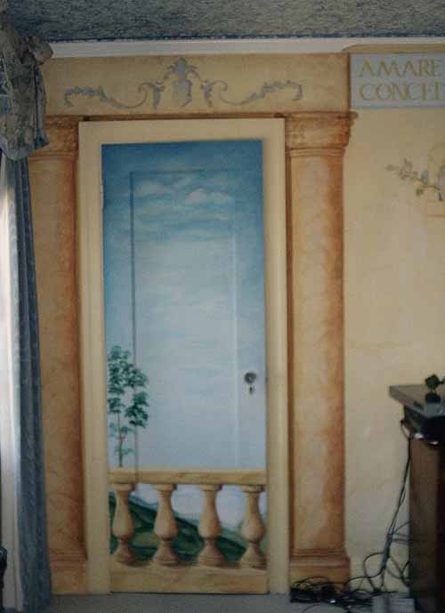 Artystyczne malowanie drzwi imitujące balkon z widokiem na niebo i drzewo, otoczone malowanymi kolumnami i dekoracyjnym fryzem.