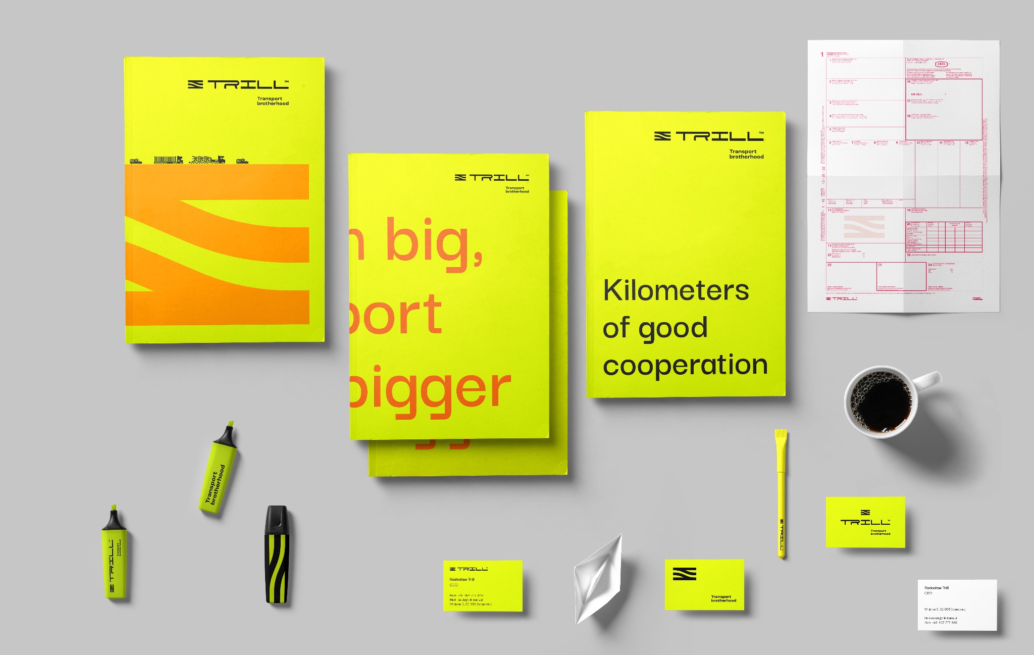 Żółte materiały firmowe Trill: katalogi z hasłami, wizytówki, dokumenty przewozowe, zakreślacze, długopis i filiżanka kawy na szarym tle. Minimalistyczny design.
