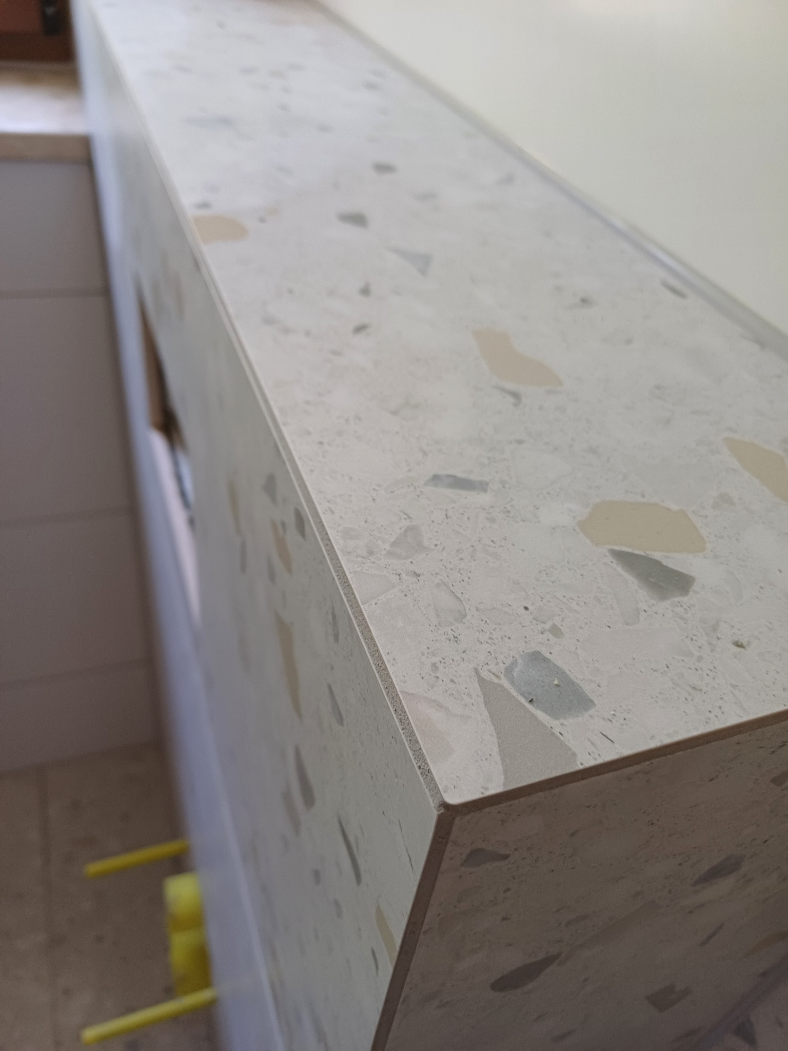 Wykończona obudowa z płytek lastryko w łazience, widok z góry na krawędź. Jasne, neutralne kolory. Ukończony element wykończenia wnętrza.