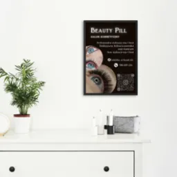 Plakat salonu kosmetycznego 'Beauty Pill' z ofertą stylizacji rzęs, brwi i paznokci, umieszczony w minimalistycznym wnętrzu na białej komodzie.