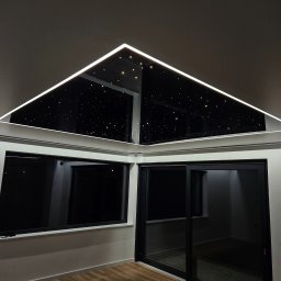 STRETCHART SPÓŁKA Z OGRANICZONĄ ODPOWIEDZIALNOŚCIĄ - Nowoczesny pokój z oknami i przesuwnymi drzwiami. Sufit napinany z efektem gwiazd i oświetleniem LED. Parkiet na podłodze. Minimalistyczny design.