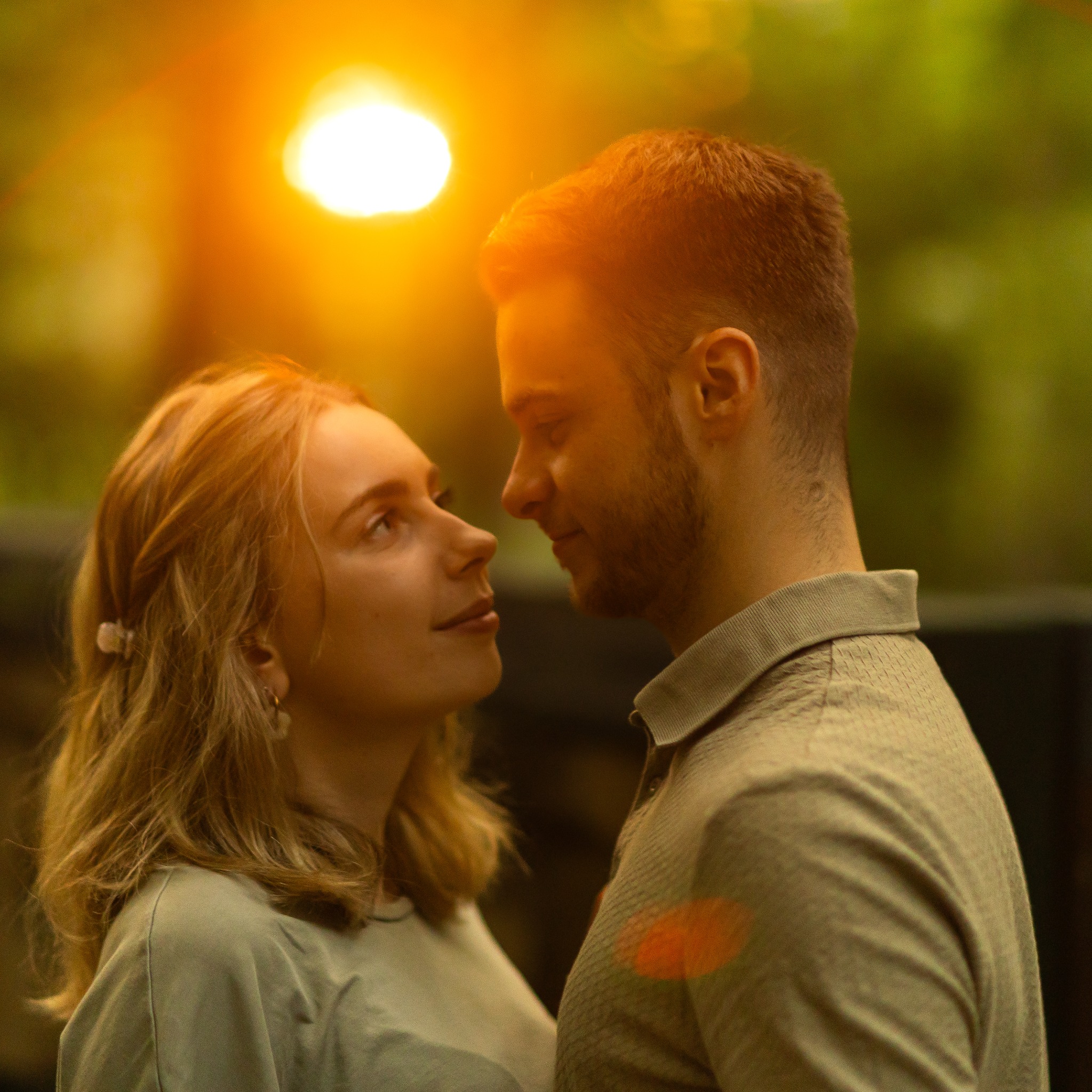 Zakochana para patrzy na siebie w Krakowie, miękkie światło, naturalne kolory, bliskość, intymność, delikatny uśmiech, swobodna atmosfera, subtelne uczucie.