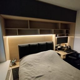 Pełna zabudowa ściany w sypialni z biurkiem oraz podświetleniem LED.