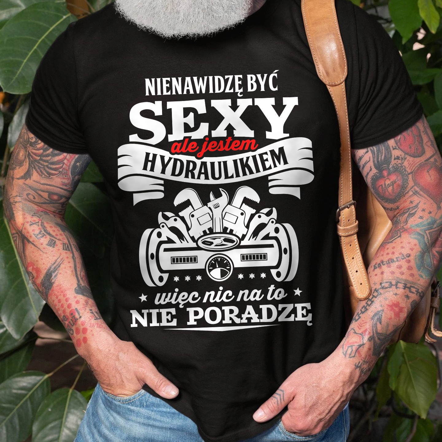 Czarna koszulka z nadrukiem hydraulicznym, prezentowana na osobie w Lublinie. Widoczne tatuaże na rękach i skórzana torba na ramieniu. Humorystyczny design.
