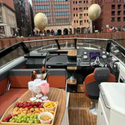 Luksusowy jacht z przekąskami i szampanem na tle malowniczego nabrzeża w Gdańsku, z dekoracyjnymi balonami, sugerujący ekskluzywną imprezę na wodzie.