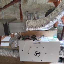 AD BUD USŁUGI Remontowo Budowlane - Montaż systemu wentylacji mechanicznej z rekuperacją w przestrzeni poddasza, widoczne izolowane przewody wentylacyjne i centrala wentylacyjna marki Tweetop.