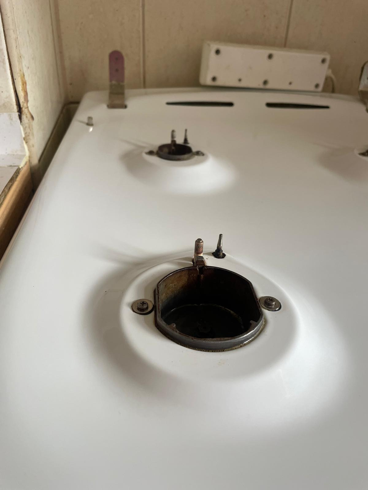 Zabrudzona, biała płyta kuchenna z palnikami wymagająca czyszczenia. Widoczne osady i pozostałości po gotowaniu. W tle beżowe płytki i biała listwa.