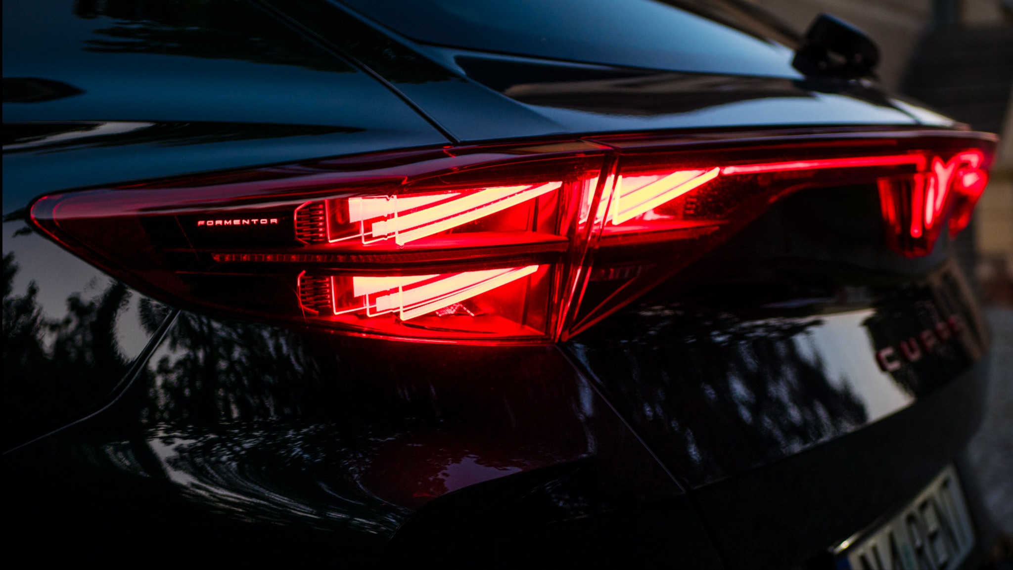 Detal tylnych świateł LED modelu Cupra Formentor, z widocznym napisem 'FORMENTOR' i częścią tablicy rejestracyjnej, w ciemnym otoczeniu.