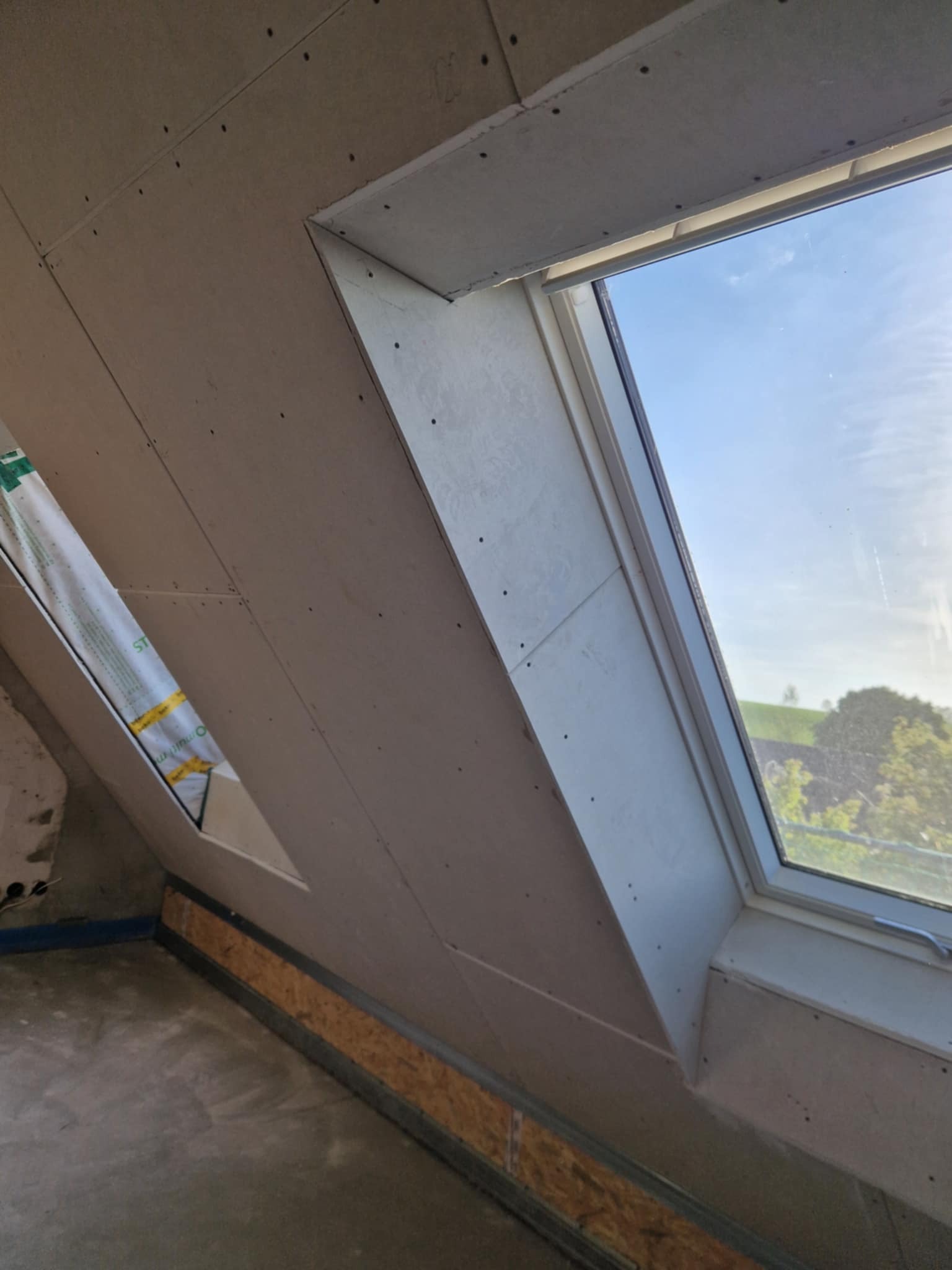 Płyty gipsowo-kartonowe na poddaszu z oknem dachowym, zamontowane w Męcinie. Widoczna konstrukcja i łączenia płyt.